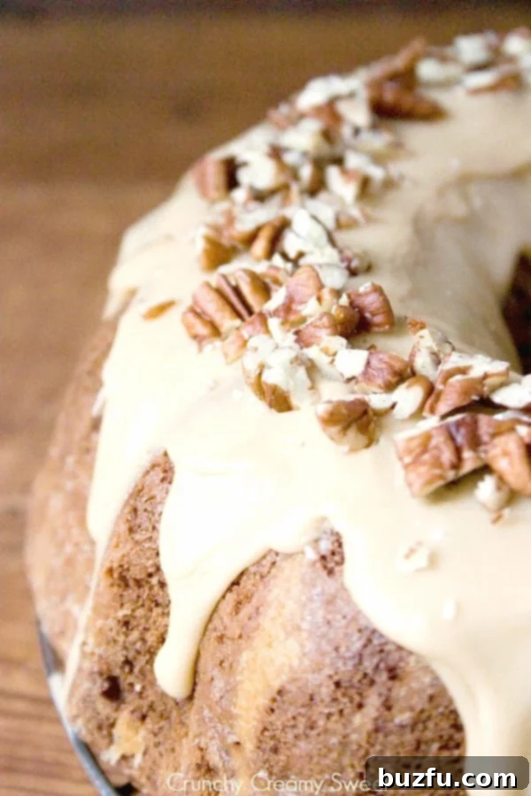 Apple Bundt Cake with Caramel Glaze - melt-in-your-mouth bundt cake with chunks of apples and sweet caramel glaze. Perfect Thanksgiving dessert idea! Side View of Apple Bundt Cake. A beautifully domed bundt cake sitting on a wire rack, showing off its intricate shape and golden crust.