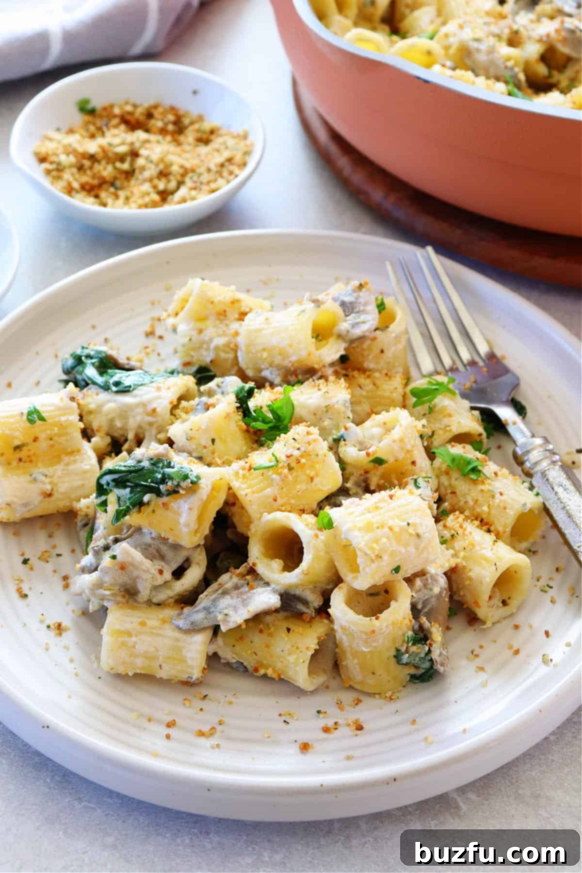 Your Weekly Meal Planner 5 A close-up, side view of creamy Boursin pasta served on a white plate, with a fork poised to capture a delicious bite.