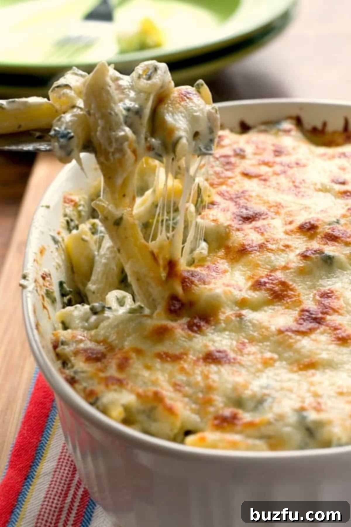 Your Weekly Meal Planner 7 A delicious side image of creamy spinach dip pasta, rich with chicken and cheese, baked to golden perfection in a casserole dish.