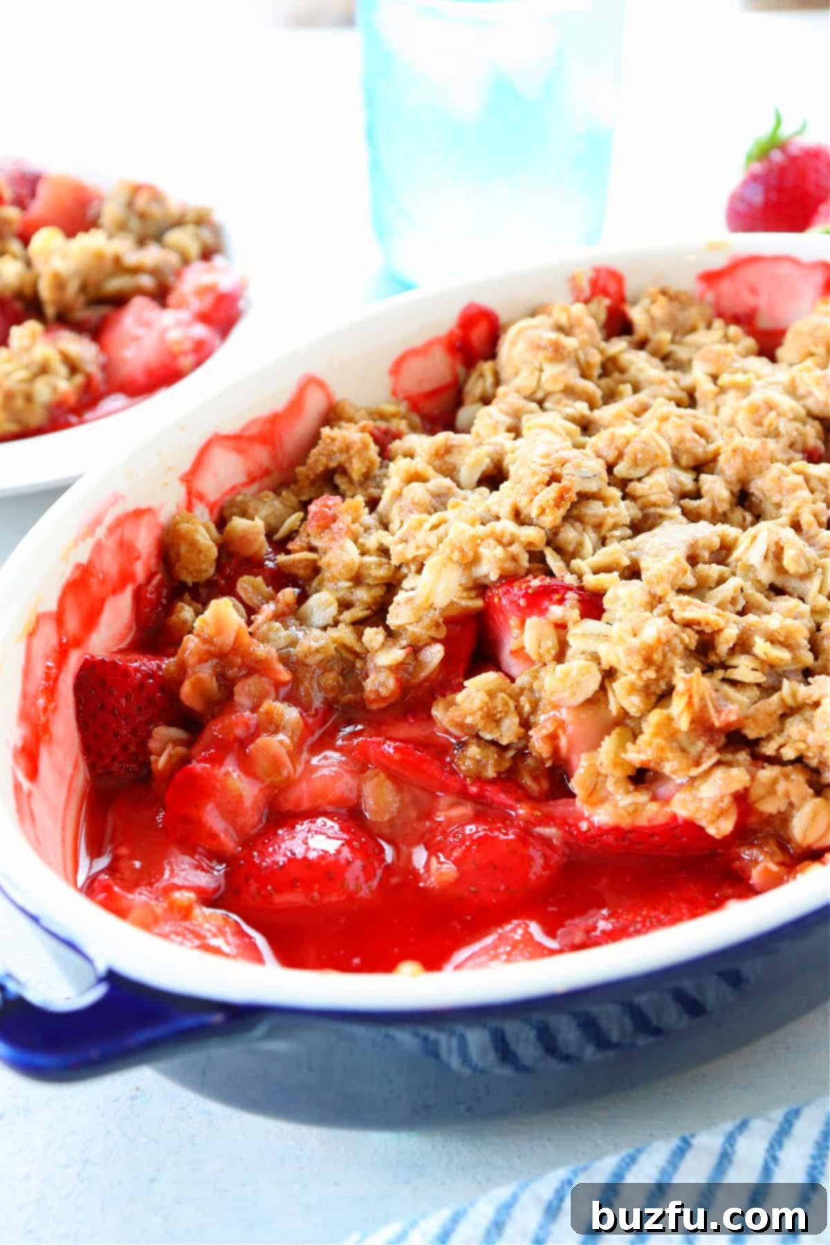 Week Six Meal Plan 9 A tantalizing side view of a golden-baked strawberry crumble in an oval baking dish, showcasing its vibrant fruit filling and crispy topping.