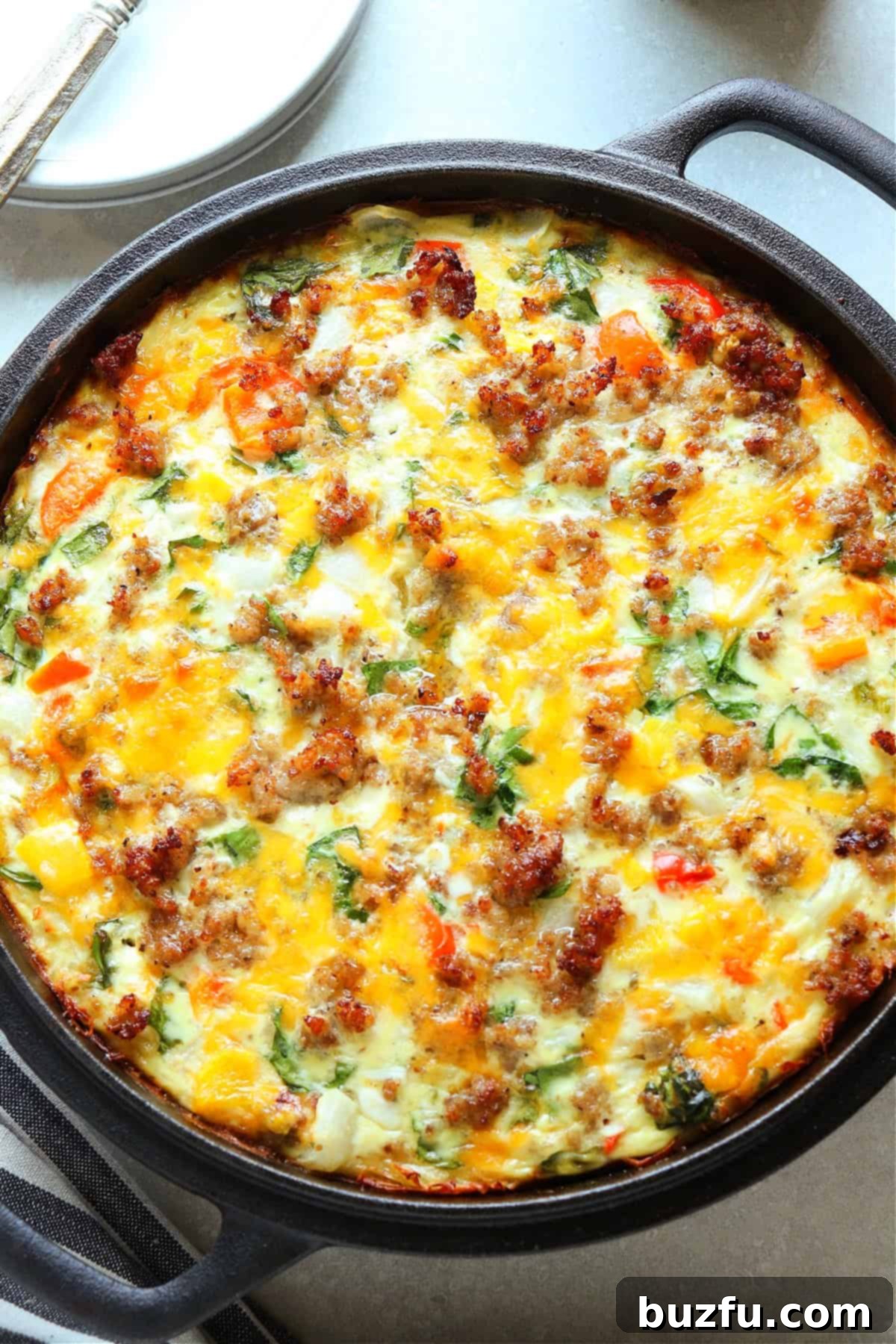 Quiche with potato crust and vegetable and sausage filling, baked in a cast iron casserole dish.