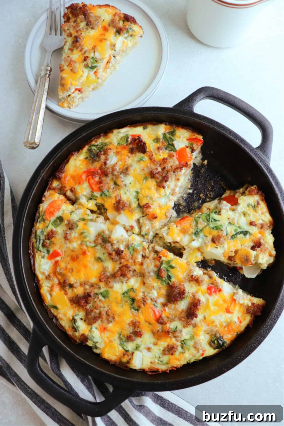 Above photo of crustless quiche in a cast iron skillet, with one slice on a plate in the upper left corner.