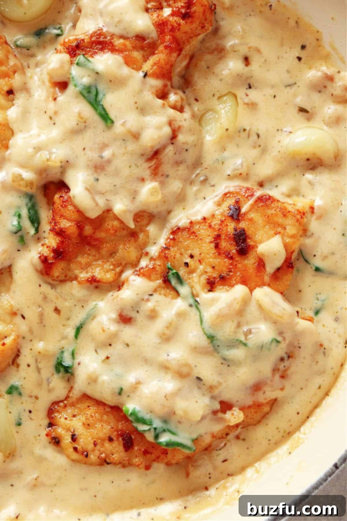 Three perfectly cooked chicken breasts nestled in a rich, creamy sauce infused with garlic and vibrant spinach, ready to be served.
