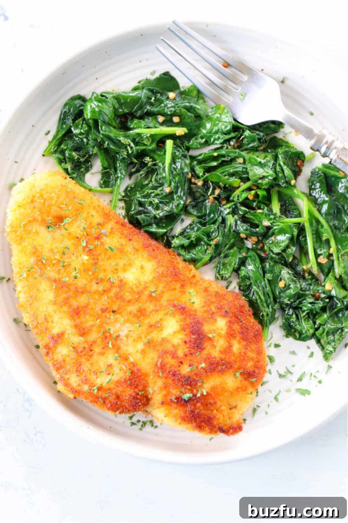 Crispy breaded chicken cutlets served alongside a vibrant portion of sautéed spinach on a plate, ready for a delicious meal.
