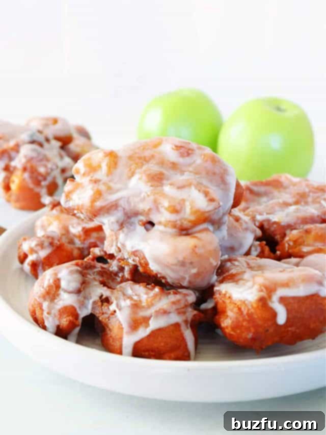 Close-up of golden-brown apple fritters, perfectly fried and inviting, showcasing their texture and autumnal appeal.