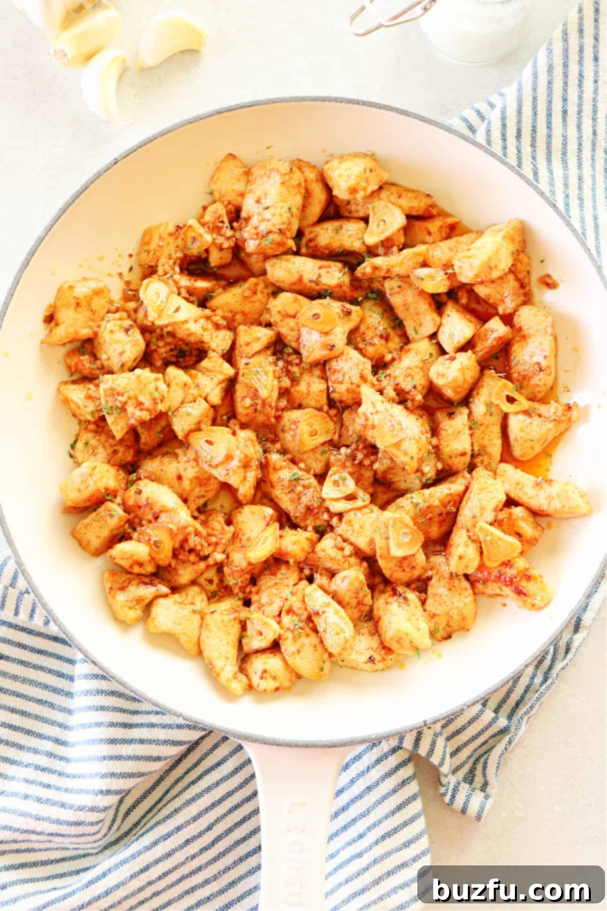 Golden brown Garlic Butter Chicken bites sautéing in a white pan, a simple and flavorful one-pan dinner idea.