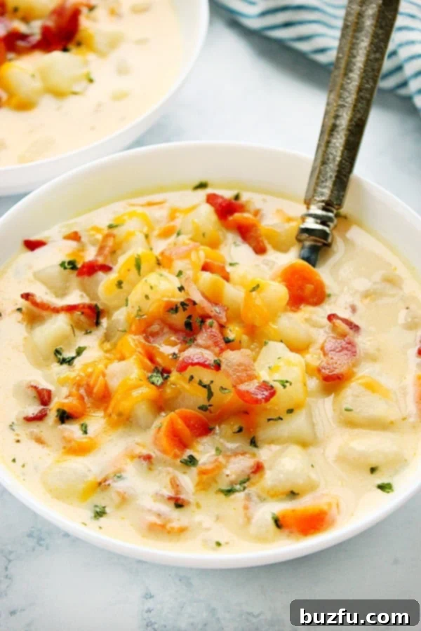 A white bowl filled with creamy Instant Pot Potato Soup, garnished with bacon and chives, with a spoon resting in it.