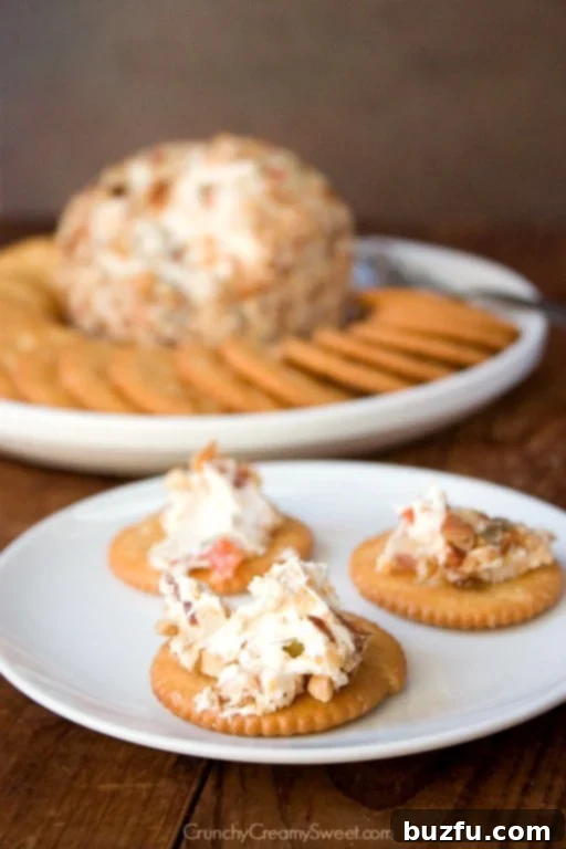 Bacon and Olive Cheese Ball coated in nuts, served with an assortment of crackers on a rustic wooden board