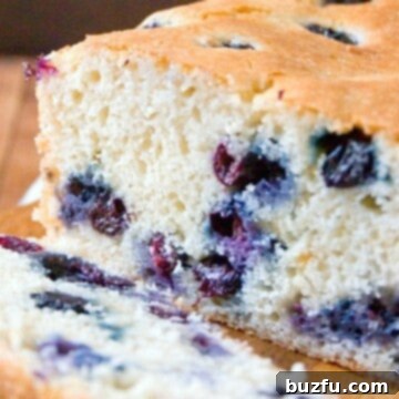 Close-up of a slice of Blueberry Quick Bread with a small bowl of fresh blueberries.