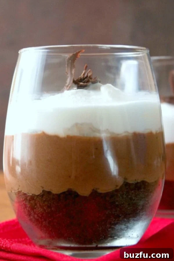 Close-up of a Chocolate Mousse Trifle in a serving glass, showcasing distinct layers of cake, mousse, and whipped cream.