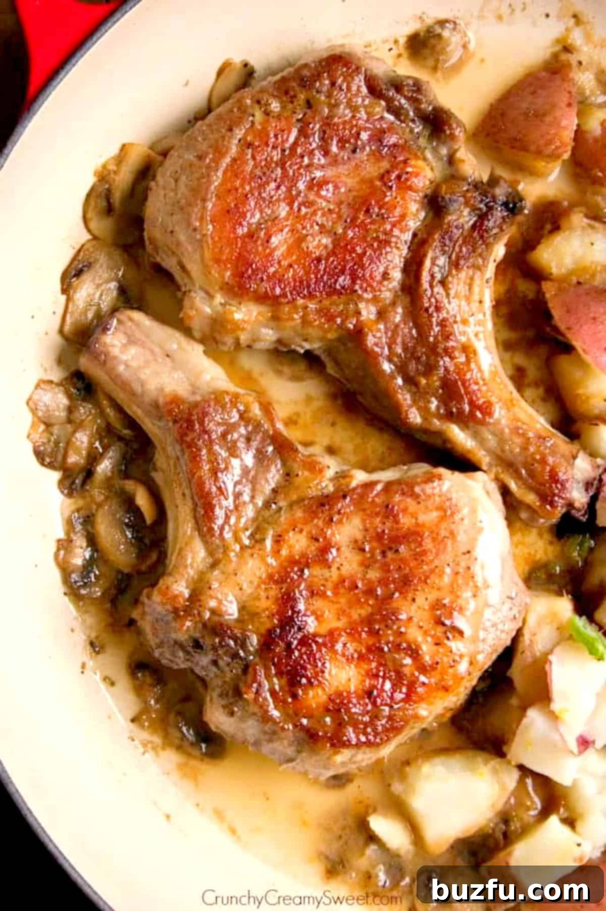 A close-up view of braised pork chops simmering in a pan with mushrooms and sauce.