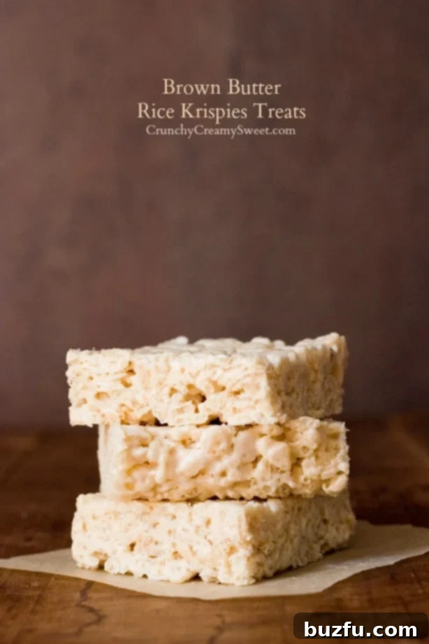 Side shot of three pieces of brown butter rice krispies treats stacked up on each other.