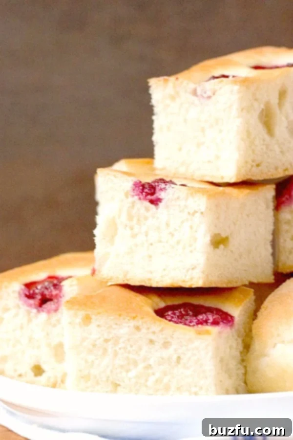 Generous slices of Raspberry Focaccia, golden and fluffy, with visible raspberries, arranged on a serving plate.