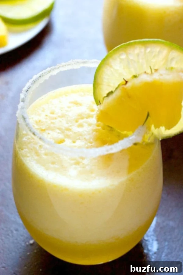 A close-up of a refreshing Fresh Pineapple Margarita in a salt-rimmed glass, garnished with a lime wedge.