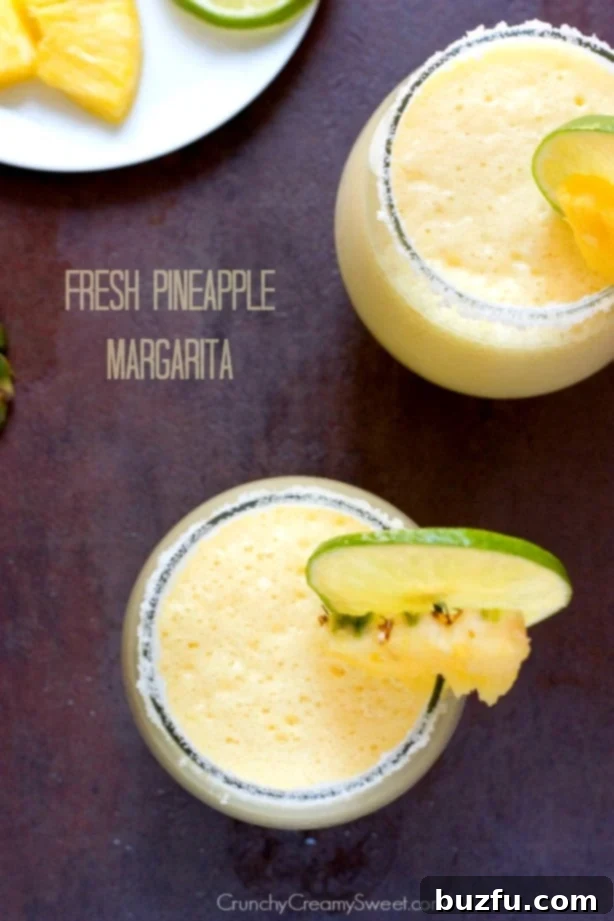 Two glasses of Fresh Pineapple Margarita, garnished with pineapple wedges, ready to be enjoyed on a sunny day.