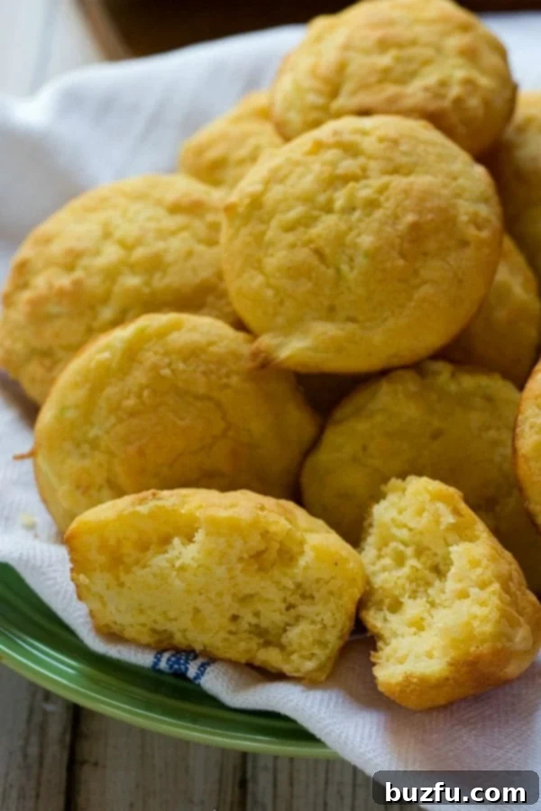 Close-up of a stack of Zucchini Cornbread Muffins on a white plate, showcasing their moist texture.