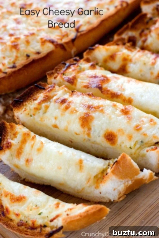Easy Cheesy Garlic Bread - perfect to go with pasta dishes or soups! So easy and so good, you won't be able to stop eating it! Side shot of sliced cheesy bread with the second half in the background, showing off the melted cheese.