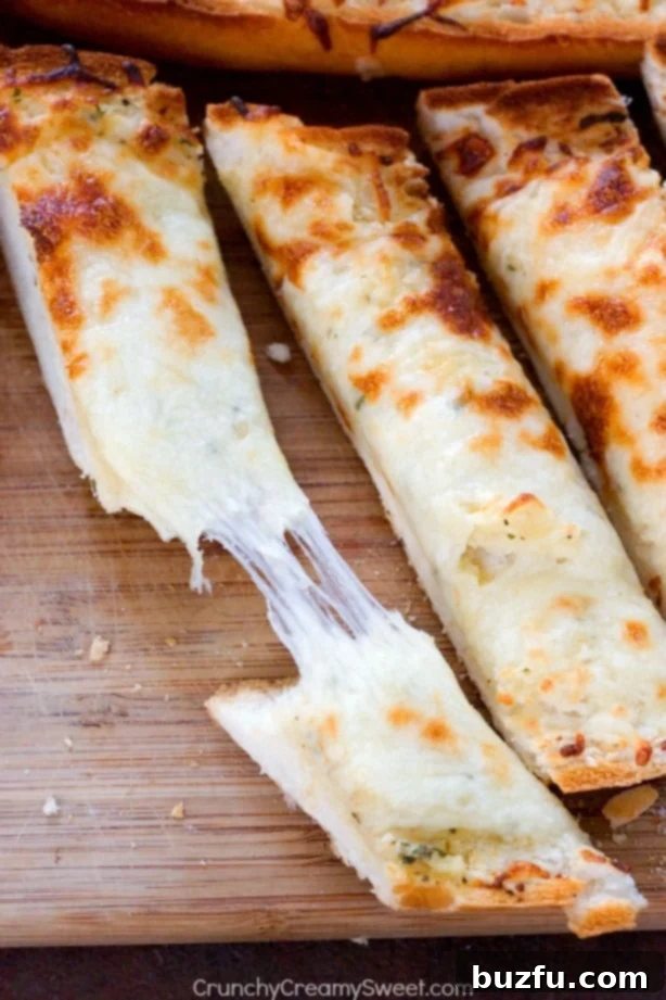 Easy Cheesy Garlic Bread - perfect to go with pasta dishes or soups! So easy and so good, you won't be able to stop eating it! Overhead shot of three sliced of cheesy garlic bread, one pulled apart with gooey cheese, ready to be eaten.