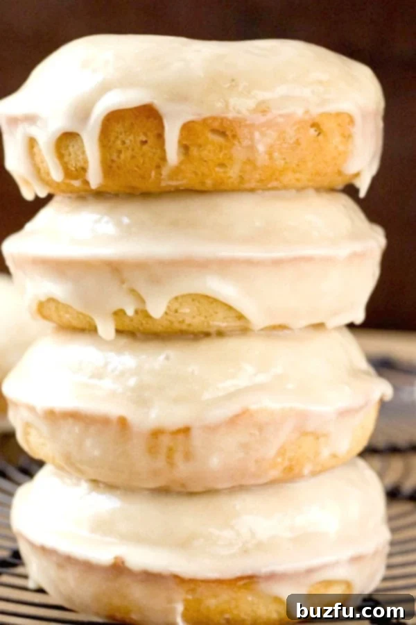 Homemade Maple Glazed Donuts: A Perfect Fall Treat to Bake at Home Stacked freshly baked maple glazed donuts, beautifully coated with a sweet, sticky glaze and a hint of cinnamon.