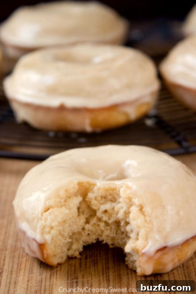 Fluffy Baked Donuts with Irresistible Maple Glaze Close-up of a single maple glazed donut, showcasing its inviting fluffy texture and the delicious, slightly messy maple glaze.