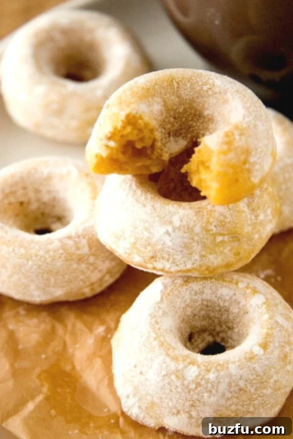 Mini Powdered Sugar Pumpkin Donuts stacked up on a plate
