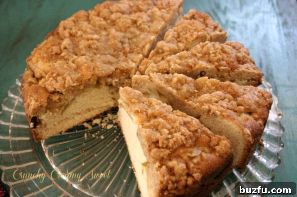 Overhead shot of an entire caramel apple coffee cake on a cake plate, showcasing its golden-brown crumb topping and glistening caramel drizzle, ready to be sliced and served.
