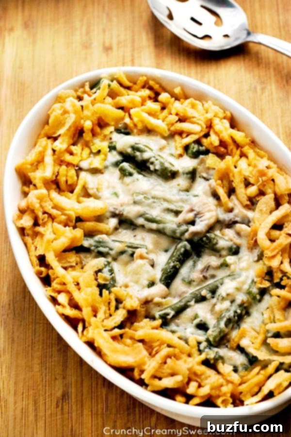 Overhead shot of a delicious, bubbly homemade green bean casserole in a white oval baking dish, topped with golden crispy onions.