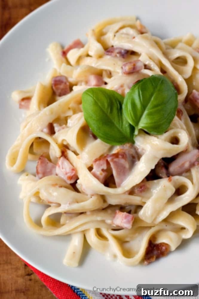 Overhead shot of pasta carbonara with basil leaves on top.