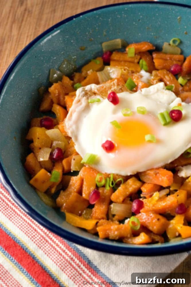 Sweet Potato Fries and Veggies Hash topped with a fried egg, garnished with green onions and pomegranate.