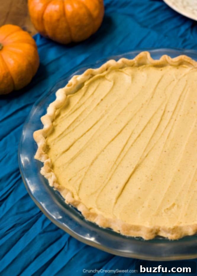 A full Pumpkin Mousse Pie resting on a textured blue napkin, showcasing its smooth, inviting surface ready for slicing.