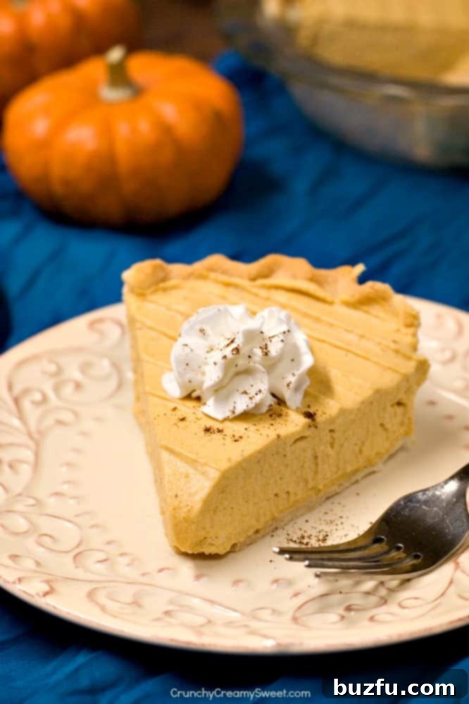 A tempting slice of Pumpkin Mousse Pie on a plate, adorned with a fluffy swirl of whipped cream and a sprinkle of nutmeg.