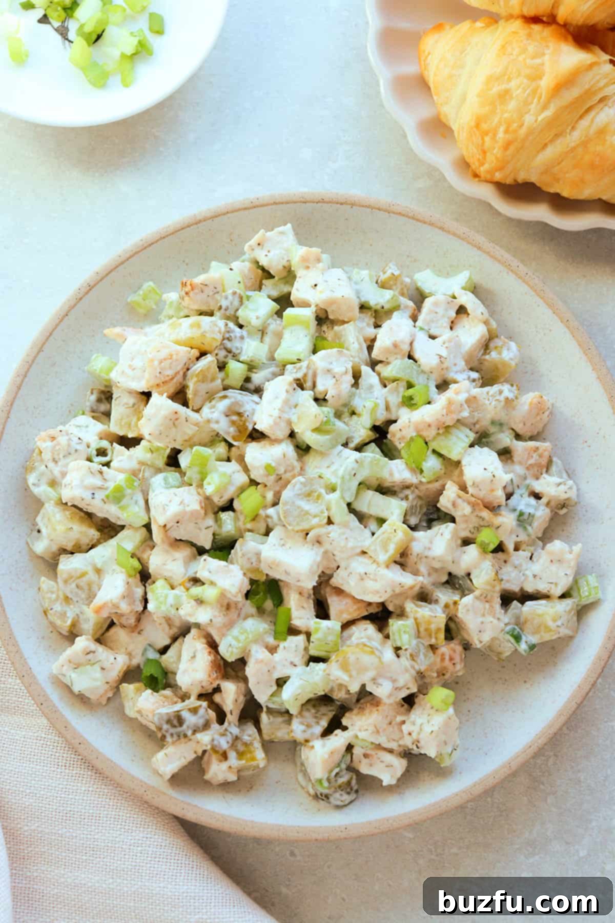 Dill Pickle Chicken Salad Delight 2 Dill pickle chicken salad served on a light brown plate with croissants in the background.