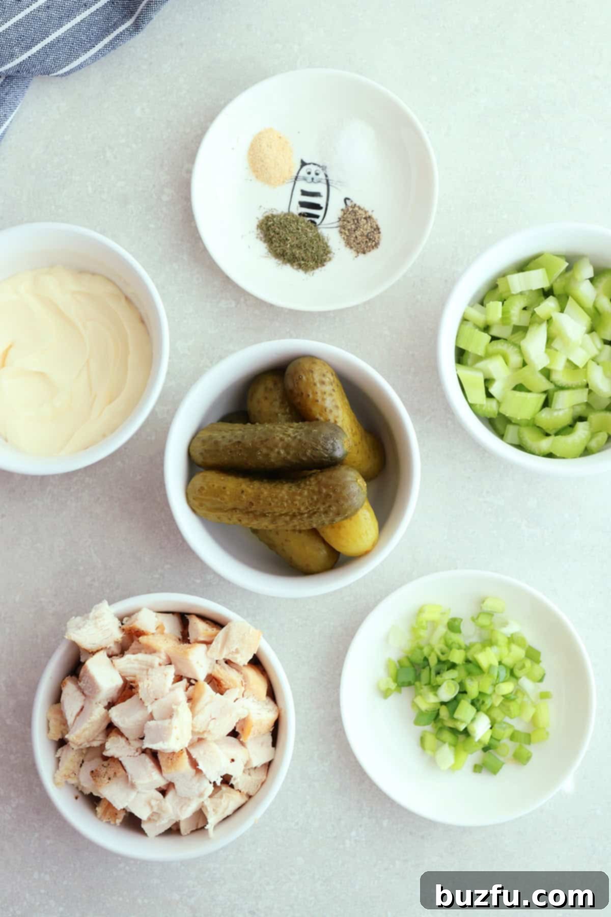 Dill Pickle Chicken Salad Delight 3 Cubed chicken, small pickles, diced celery, mayo, and seasoning in small bowls on a gray board.
